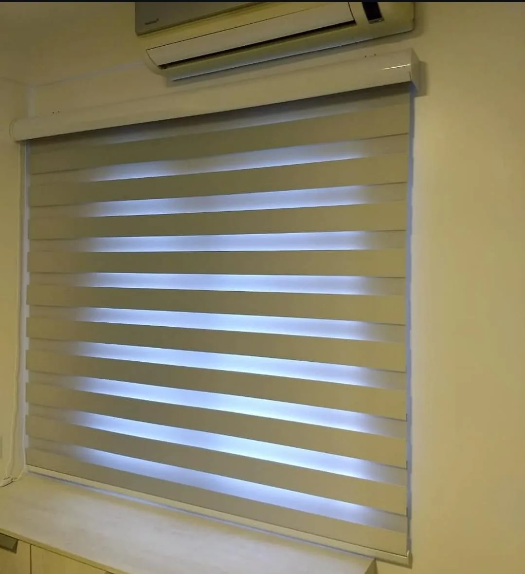Cortina rolô double vision bege instalada em janela de quarto