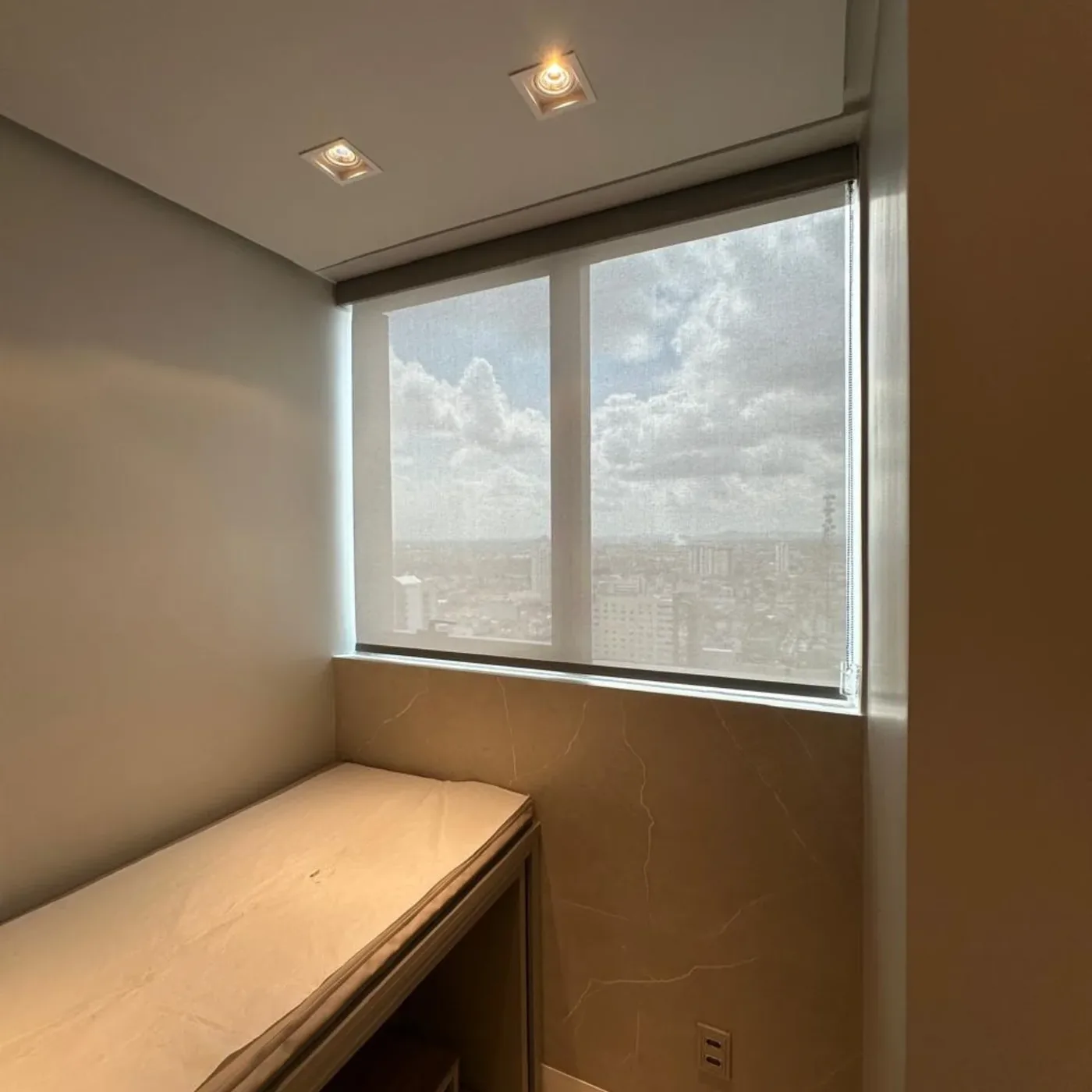 Cortina rolô em quarto com bancada e vista para a cidade