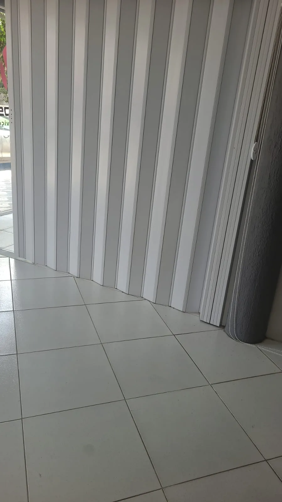 Porta sanfonada branca em PVC instalada em vão de estabelecimento comercial