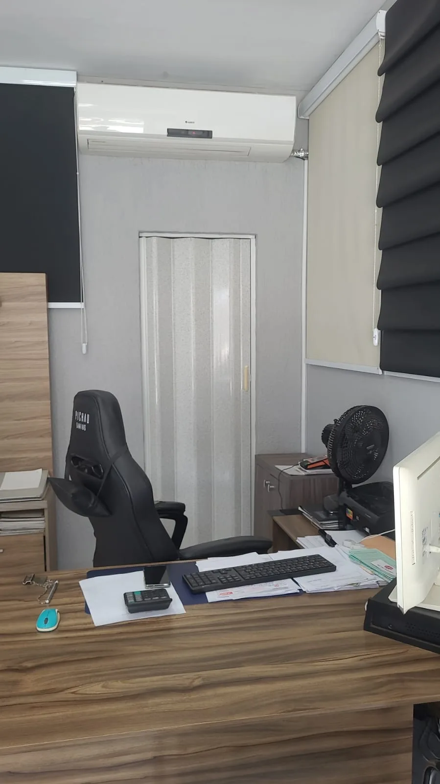 Porta sanfonada branca instalada em escritório com persianas