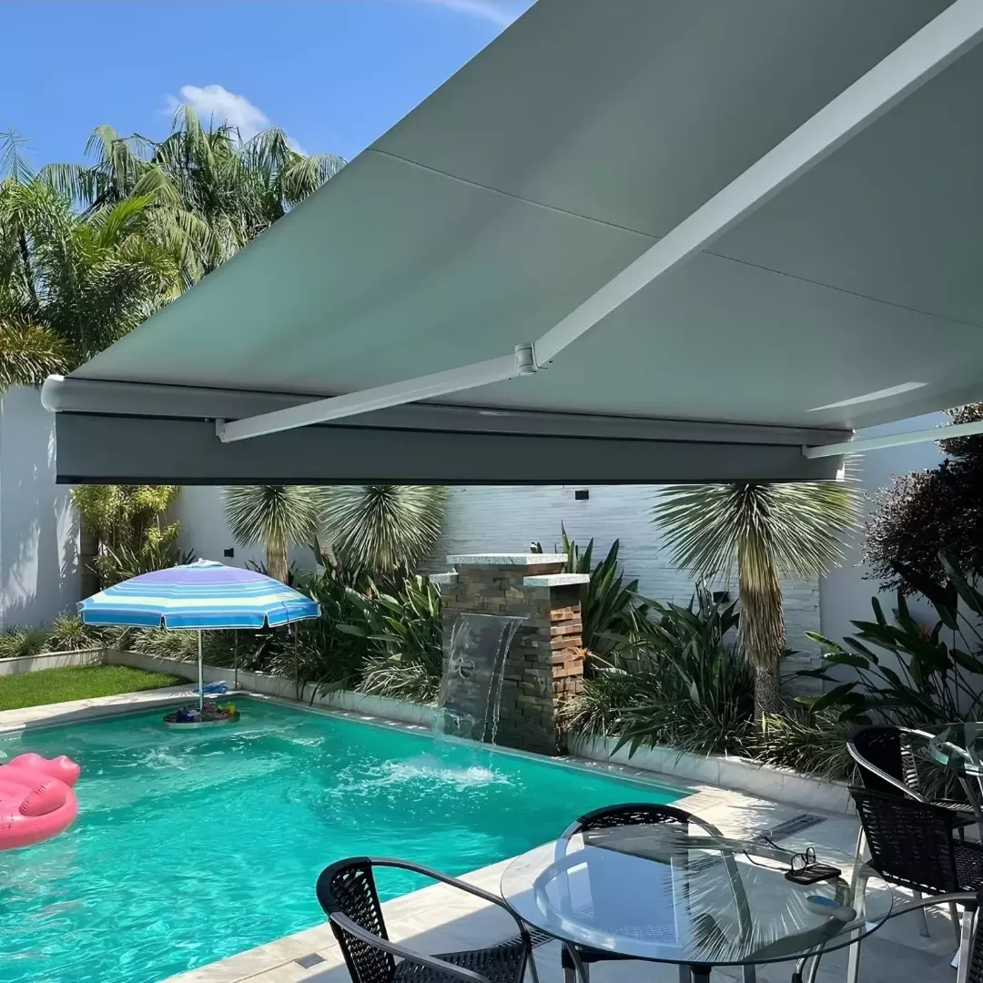 Toldo retrátil verde claro cobrindo área gourmet com piscina